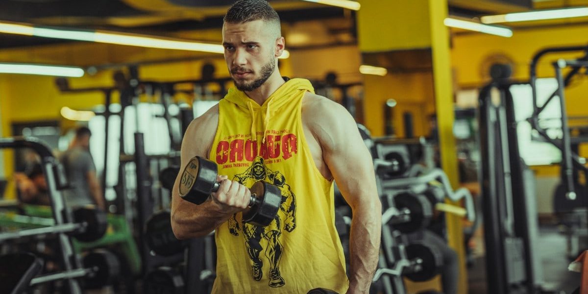 a man in a gym holding a pair of dumbs