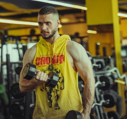 a man in a gym holding a pair of dumbs