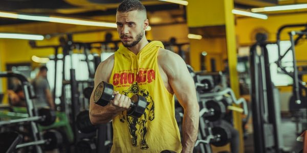 a man in a gym holding a pair of dumbs